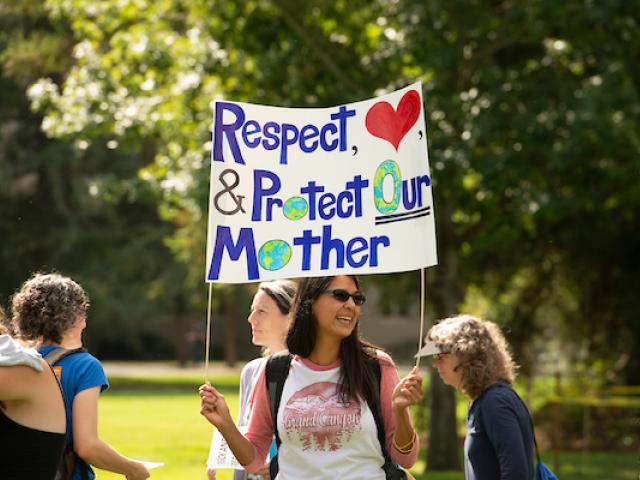 Person holding a sign that says "respect, love and protect our mother earth"